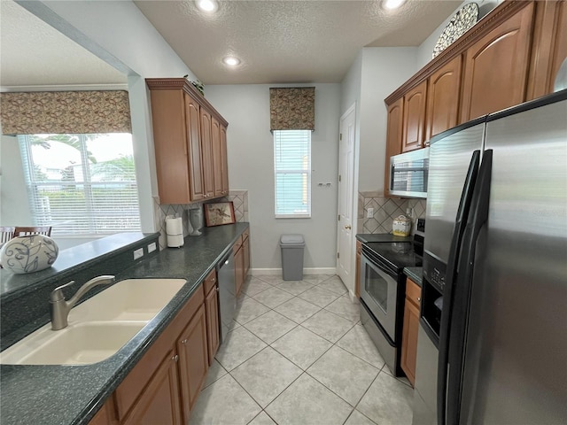 kitchen featuring dark countertops, brown cabinetry, stainless steel appliances, and a sink