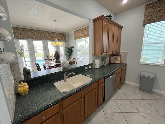 kitchen with a textured ceiling, a sink, dishwasher, brown cabinetry, and dark countertops