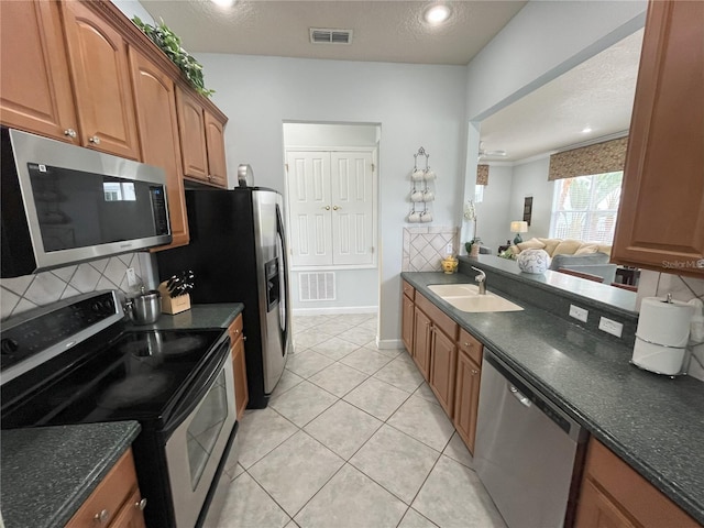 7762 Linkside Loop, Reunion, FL 34747 - kitchen featuring appliances with stainless steel finishes, a sink, decorative backsplash, brown cabinets, and light tile patterned flooring