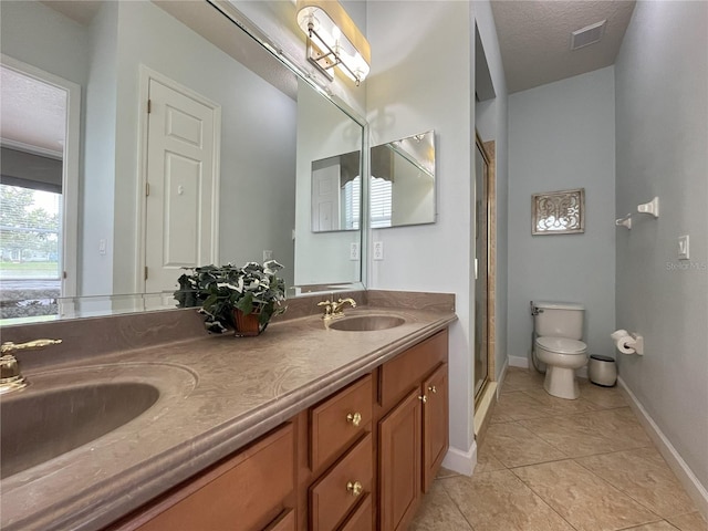 bathroom featuring vanity, tile patterned flooring, a textured ceiling, toilet, and a shower with door