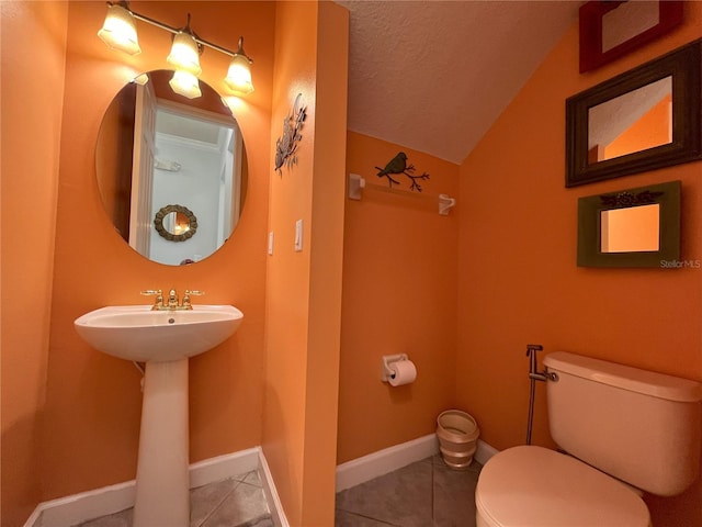 bathroom featuring toilet, vaulted ceiling, sink, tile patterned floors, and a textured ceiling