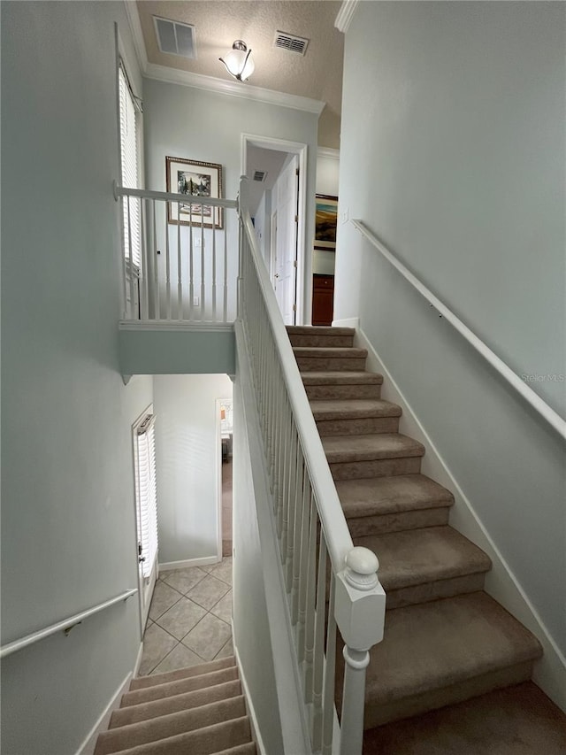 stairs with a textured ceiling, tile patterned floors, crown molding, and a wealth of natural light