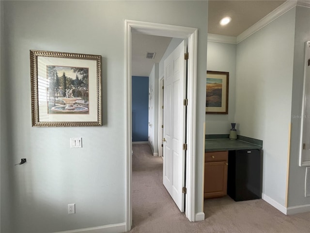 hallway with ornamental molding and light carpet