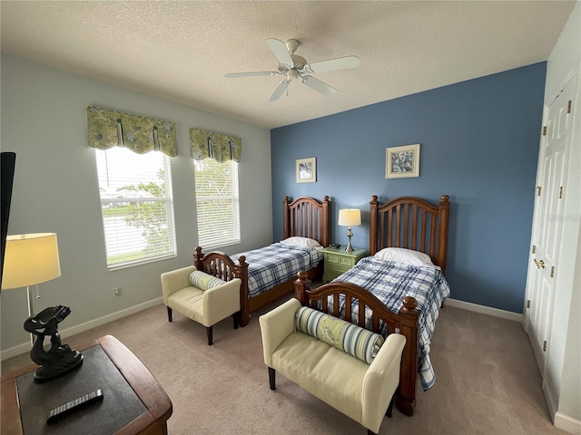 bedroom featuring light colored carpet, a textured ceiling, and ceiling fan