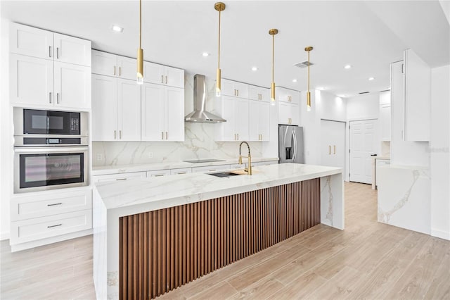 kitchen featuring tasteful backsplash, light wood-type flooring, wall chimney range hood, white cabinets, and black appliances