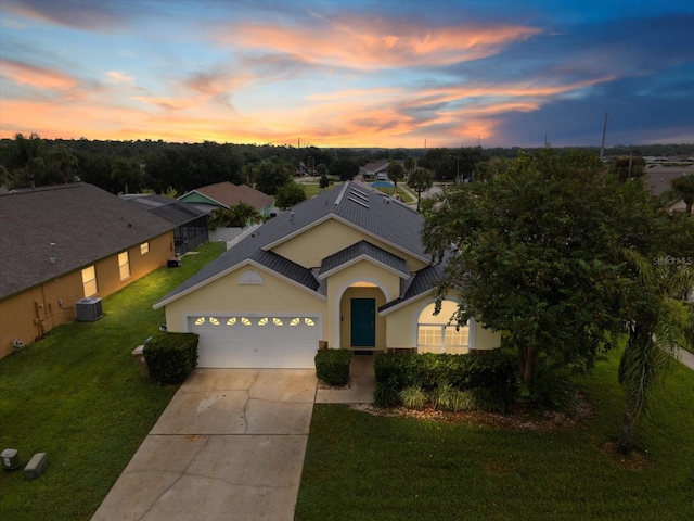 view of front facade featuring a lawn, a garage, and central AC unit