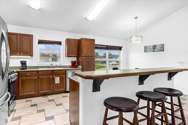 kitchen featuring light tile patterned floors, a kitchen bar, hanging light fixtures, stainless steel appliances, and sink