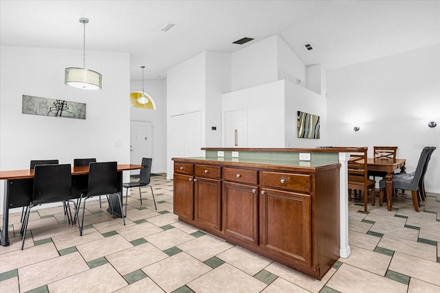 kitchen featuring pendant lighting, light tile patterned floors, and high vaulted ceiling