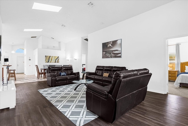 carpeted living room with high vaulted ceiling and a skylight