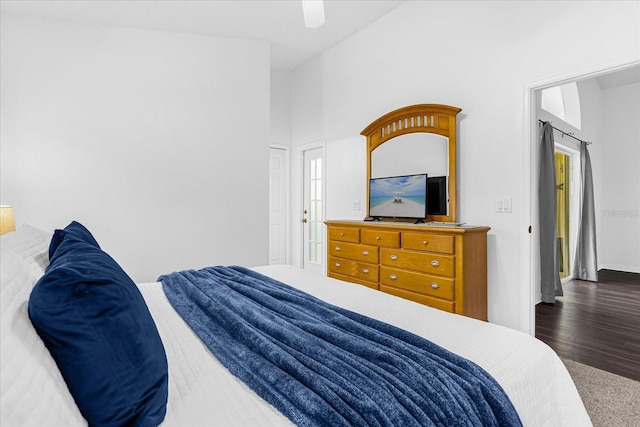 bedroom with ceiling fan, dark hardwood / wood-style floors, and a towering ceiling