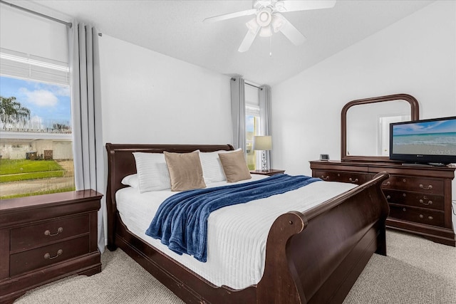 bedroom with vaulted ceiling, light carpet, ceiling fan, and multiple windows