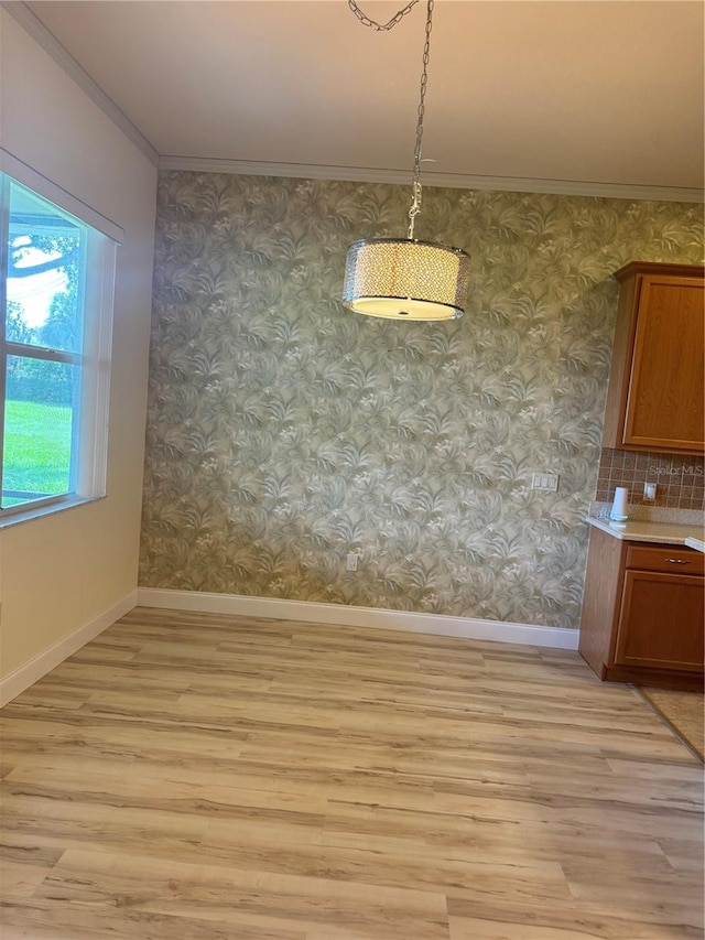 unfurnished dining area featuring crown molding and light wood-type flooring