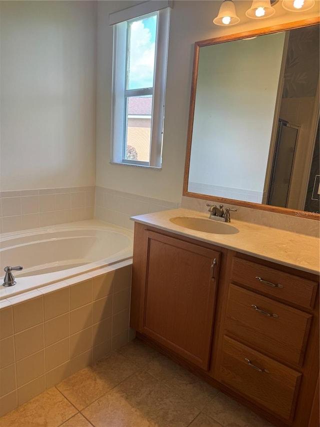 bathroom featuring tiled tub, tile patterned floors, a wealth of natural light, and vanity