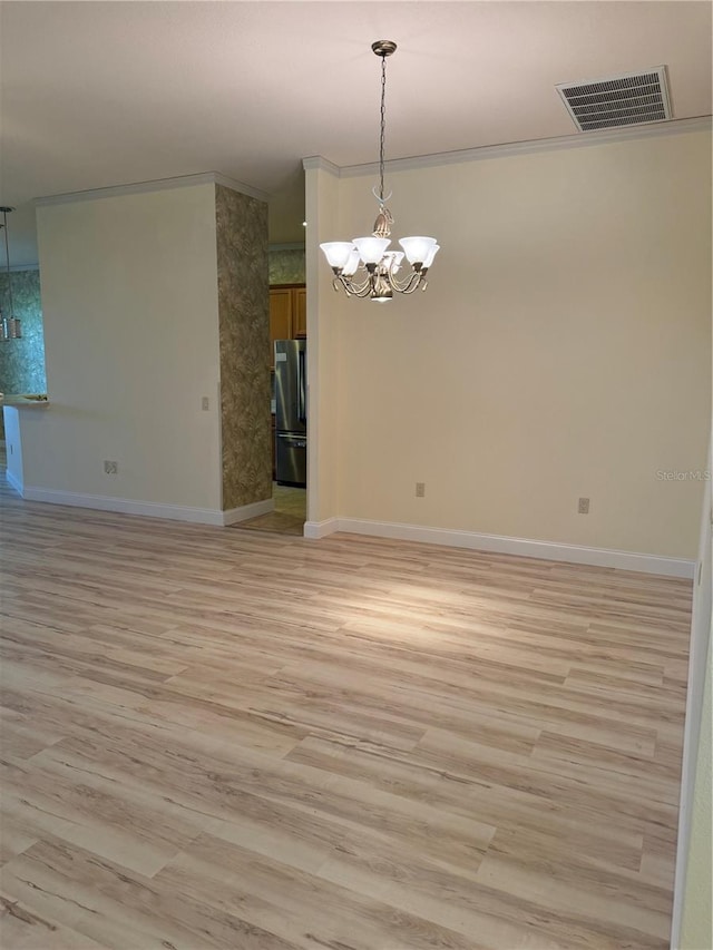 spare room with light hardwood / wood-style flooring and an inviting chandelier