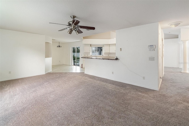 unfurnished living room with ceiling fan, decorative columns, and light colored carpet