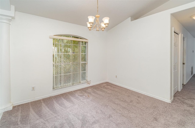 carpeted empty room featuring vaulted ceiling, a chandelier, and ornate columns