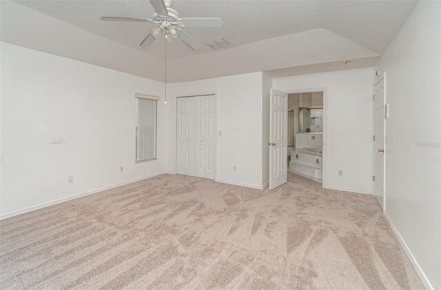 unfurnished bedroom with ceiling fan, ensuite bathroom, vaulted ceiling, and light colored carpet