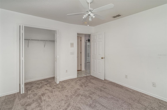 unfurnished bedroom featuring ceiling fan, a closet, and light colored carpet