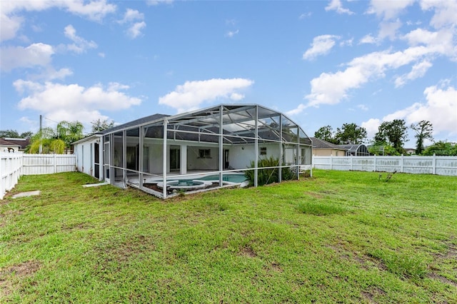 rear view of property featuring a lawn, glass enclosure, and a fenced in pool