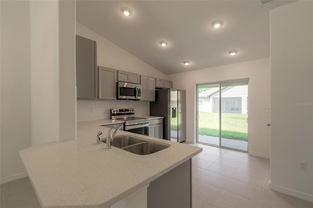 kitchen with light tile patterned flooring, lofted ceiling, kitchen peninsula, backsplash, and stainless steel appliances