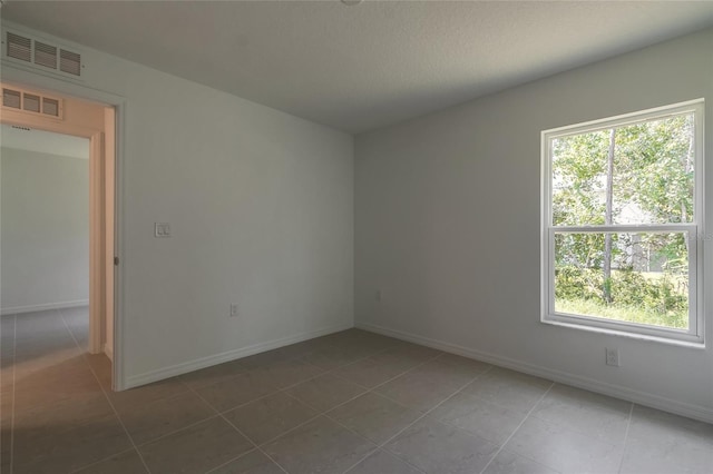 empty room with a wealth of natural light and tile patterned floors