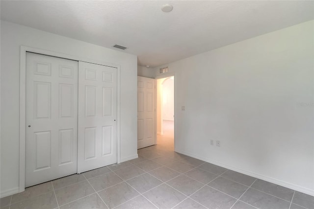 unfurnished bedroom featuring a closet and light tile patterned floors