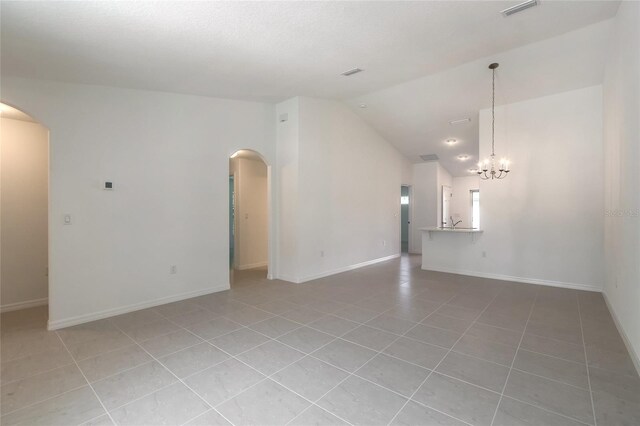 empty room with a chandelier, lofted ceiling, and light tile patterned floors