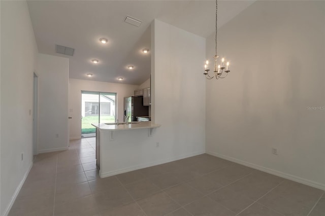 tiled empty room featuring an inviting chandelier, sink, and vaulted ceiling