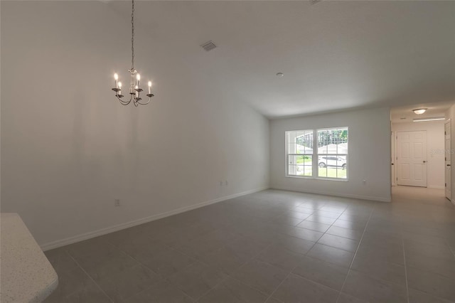 tiled spare room with a notable chandelier