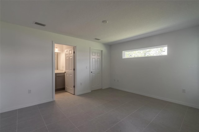 unfurnished bedroom with tile patterned floors and ensuite bathroom