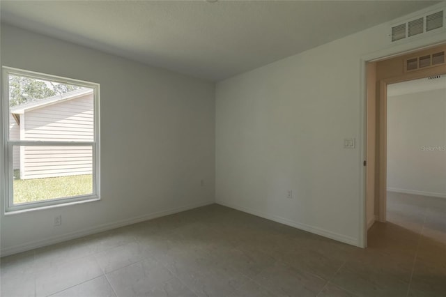 spare room featuring tile patterned flooring and a wealth of natural light