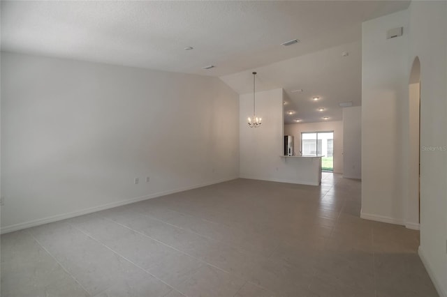 tiled empty room with a notable chandelier and lofted ceiling