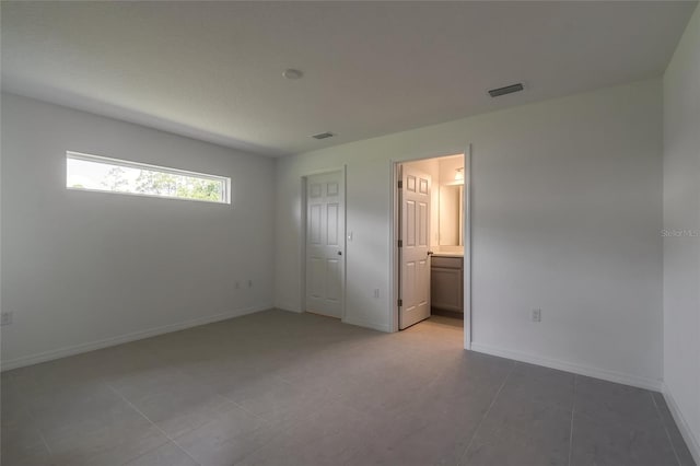 unfurnished bedroom with a closet, tile patterned floors, and connected bathroom