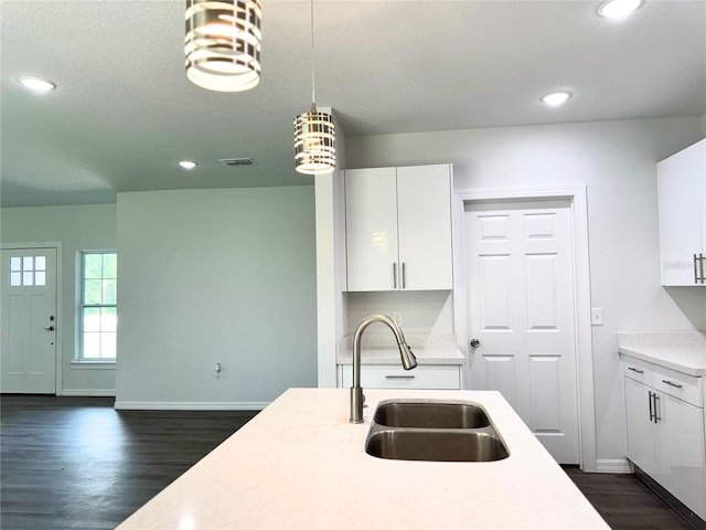 kitchen with sink, dark hardwood / wood-style flooring, white cabinets, and decorative light fixtures