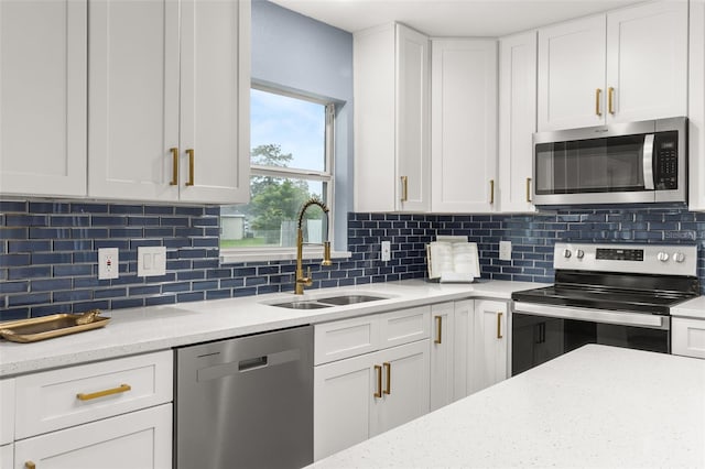 kitchen featuring sink, backsplash, stainless steel appliances, and white cabinets