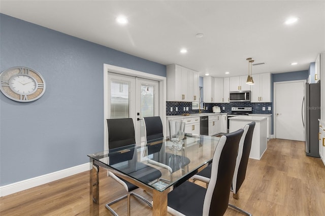 dining area with french doors, light wood-type flooring, and sink