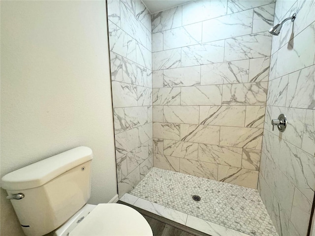 bathroom featuring tiled shower and toilet