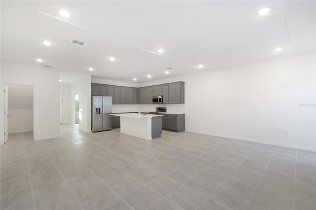 kitchen featuring gray cabinets, light tile patterned floors, an island with sink, and stainless steel appliances