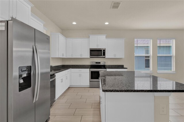 kitchen with white cabinets, a kitchen island, appliances with stainless steel finishes, and light tile patterned floors