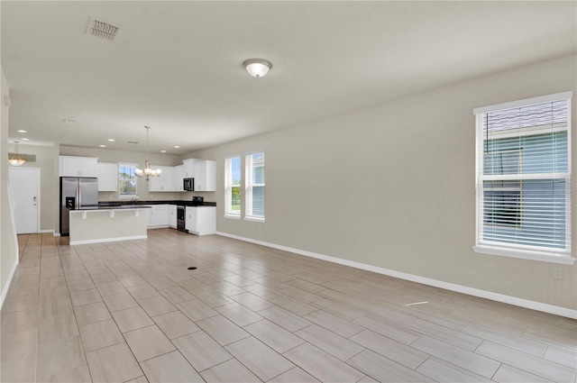 unfurnished living room featuring a chandelier