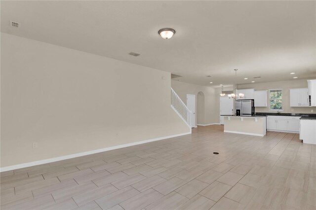 unfurnished living room featuring sink, a chandelier, and light tile patterned floors