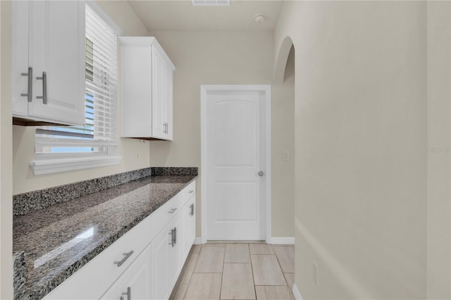 kitchen featuring dark stone counters, light tile patterned flooring, and white cabinets