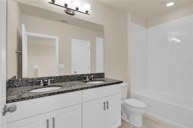 full bathroom featuring toilet, tiled shower / bath combo, and double sink vanity