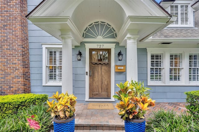 view of exterior entry featuring a shingled roof