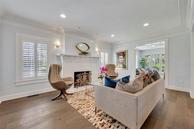 living area with recessed lighting, visible vents, a brick fireplace, wood finished floors, and baseboards