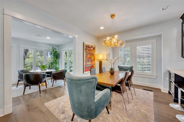 dining space featuring a notable chandelier, baseboards, wood finished floors, and recessed lighting