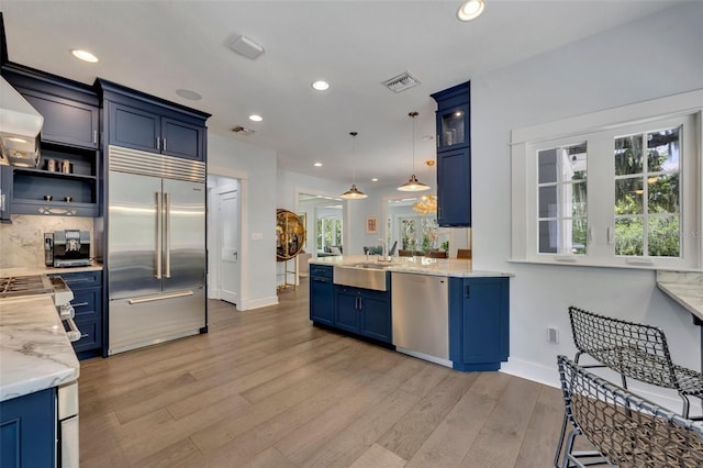 kitchen with blue cabinets, stainless steel appliances, visible vents, glass insert cabinets, and pendant lighting