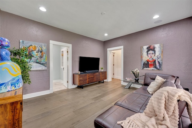 living area with a textured wall, recessed lighting, wood finished floors, and baseboards