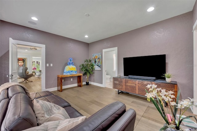 living room with a textured wall, light wood finished floors, recessed lighting, and baseboards