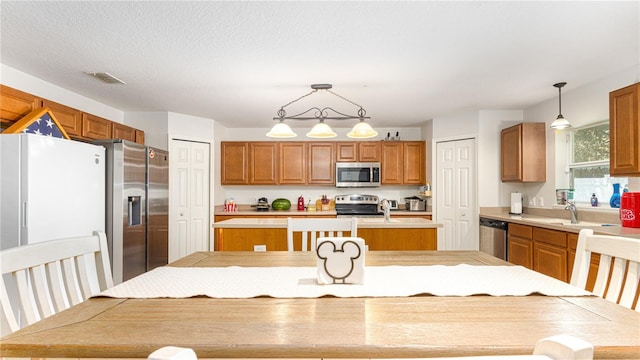 kitchen with sink, decorative light fixtures, a center island, and stainless steel appliances